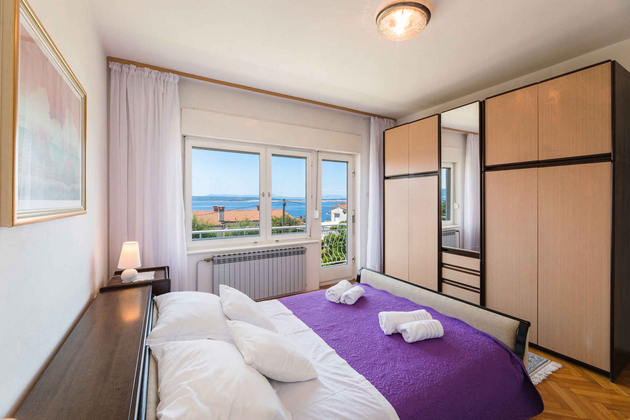 Hotellihuone, jossa on sänky, ikkunasta avautuva näkymä, patteri ja vaatekaappi.