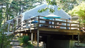 Une maison avec une terrasse en bois et un parasol bleu.