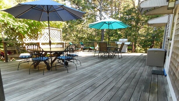 Une terrasse en bois avec des meubles d’extérieur et des parasols.