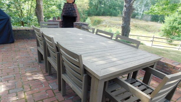 An outdoor patio with a brick floor, a wooden table, and chairs. - Path to Pond, Private Location, Sweet Home! (CS0031) (Wellfleet)