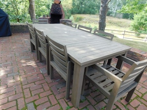 Un patio al aire libre con piso de ladrillo, una mesa de madera y sillas.