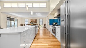Une cuisine moderne dotée d’un grand îlot central, d’appareils électroménagers en acier inoxydable et d’un plancher en bois.