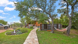 A stone pathway leading to a rustic cabin with a hammock and a small shed. - Fredericksburg, TX Cabin - River Access - Romantic Getaway (Fredericksburg)