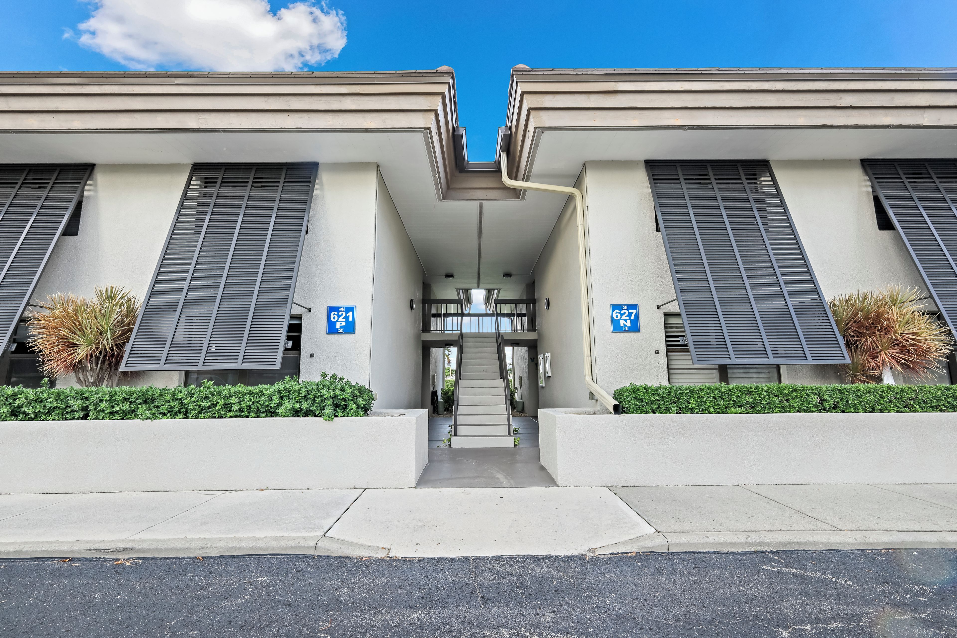A modern building with two wings, each marked with a blue sign indicating parking spaces.