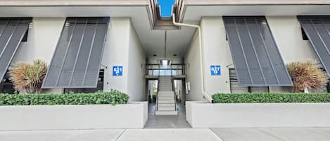 A modern building with two wings, each marked with a blue sign indicating parking spaces.