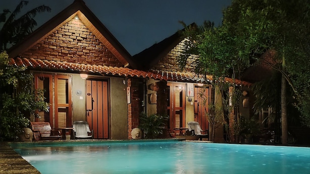 Une maison à deux étages avec une piscine, dotée d’une façade en briques et de portes en bois.