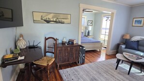 Un salon avec un plancher en bois, une table à manger avec des chaises, un canapé, une table basse et un ventilateur de plafond.