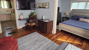 Une chambre à coucher comprenant un lit, un bureau, une chaise, un téléviseur et un ventilateur de plafond.