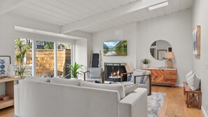 Ein modernes Wohnzimmer mit Kamin, großem Fenster und Blick auf eine Holzterrasse.