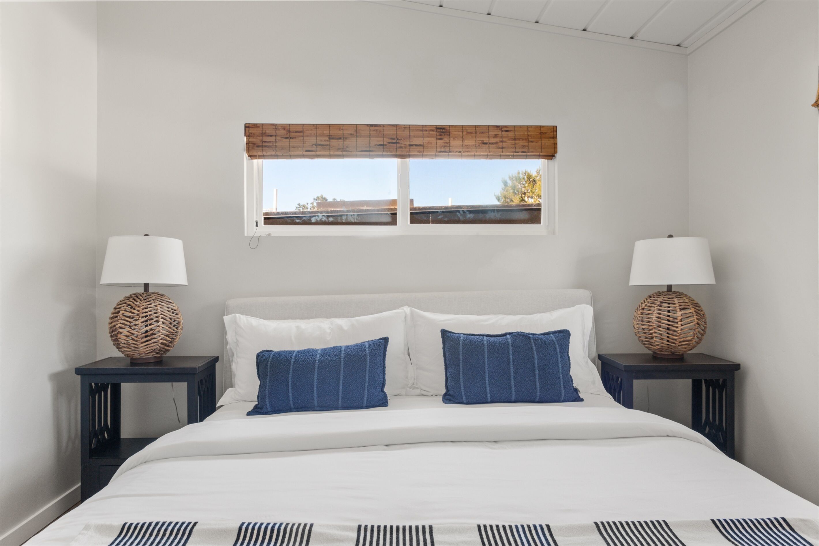 Ein Schlafzimmer mit einem Bett, zwei Nachttischen, einem Fenster mit Blick und einem Deckenventilator.