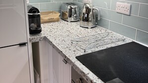 Una cocina con armarios blancos, encimera de granito, tostadora, tetera y cafetera.