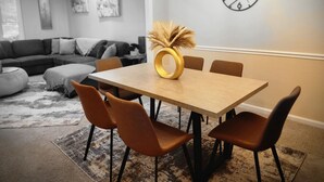 Een eethoek met een houten tafel, bruine stoelen en een decoratieve vaas.