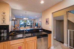 A modern kitchen with a central island, built-in dishwasher, and a dining area with a view.