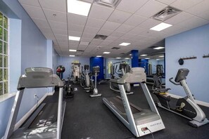 Une salle de sport équipée de tapis de course, de vélos elliptiques et d'appareils de musculation.