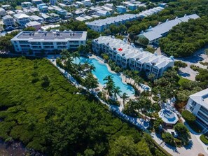 A resort with a large swimming pool surrounded by palm trees and multiple hotel buildings.