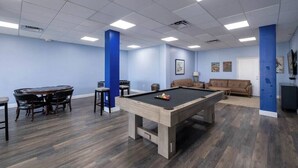 Une salle de loisirs équipée d’une table de billard, d’une table à manger avec des chaises et d’un canapé.