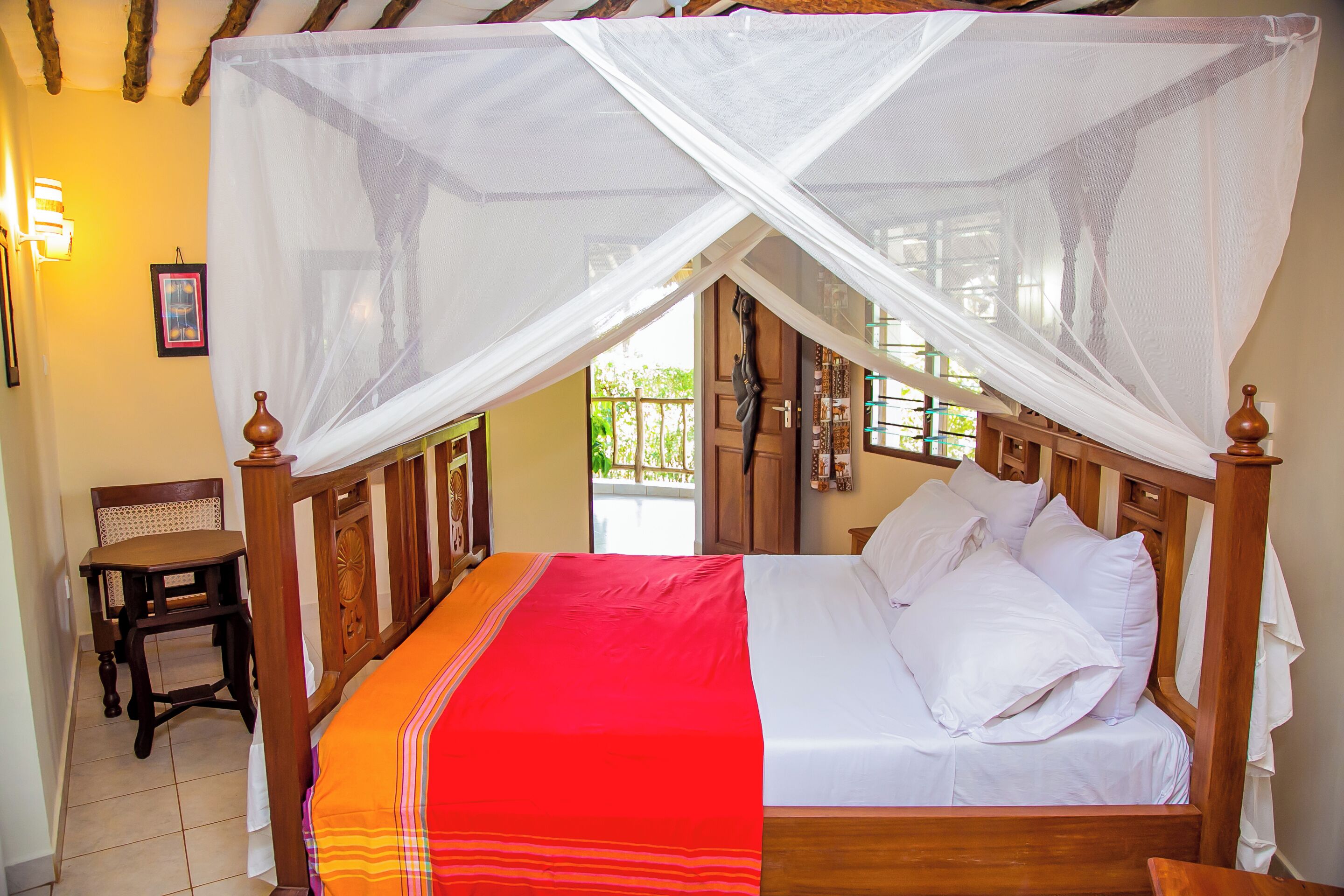 A bed with a canopy, a wooden headboard, and a red and white bedspread.