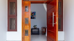 Une porte en bois avec des panneaux de verre, un tableau accroché au mur, une petite table avec une plante et une chaise.