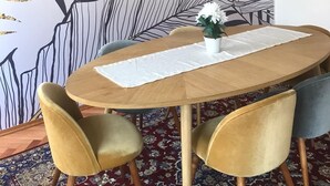 Un comedor con una mesa redonda de madera, dos sillas y un amplio mural de hojas en la pared.