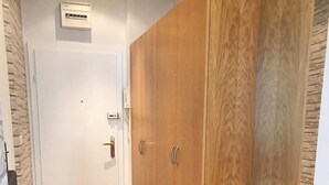 Un pasillo con un armario de madera, una alfombra de entrada y un equipo de aire acondicionado de pared.