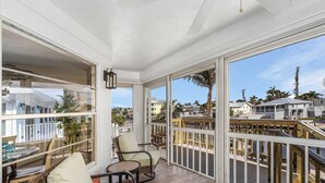 A balcony with wicker furniture, large windows, and a view of the cityscape. - 122 Primo Dr 3 Bedroom Home by RedAwning (Fort Myers Beach)