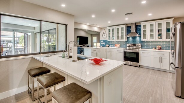 Una cocina moderna con armarios blancos, una isla de mármol y un tazón rojo.