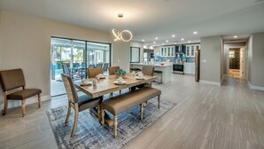 Un comedor espacioso con una mesa y sillas de madera, un banco y una lámpara colgante moderna.