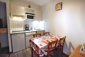 Compact kitchen with microwave, coffee maker, and dishwasher. Dining area with table and four chairs.