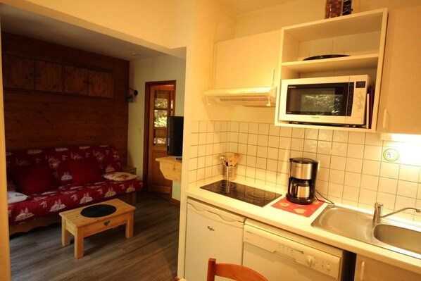 A compact living space with a kitchenette, a microwave, a coffee maker, and a dishwasher.