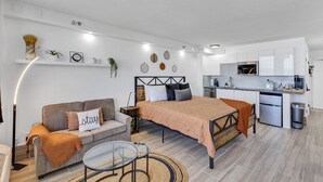A modern, compact living space with a bed, sofa, and kitchenette. - Beachfront Remodeled Studio in Daytona Beach with King-Size Bed (Daytona Beach)
