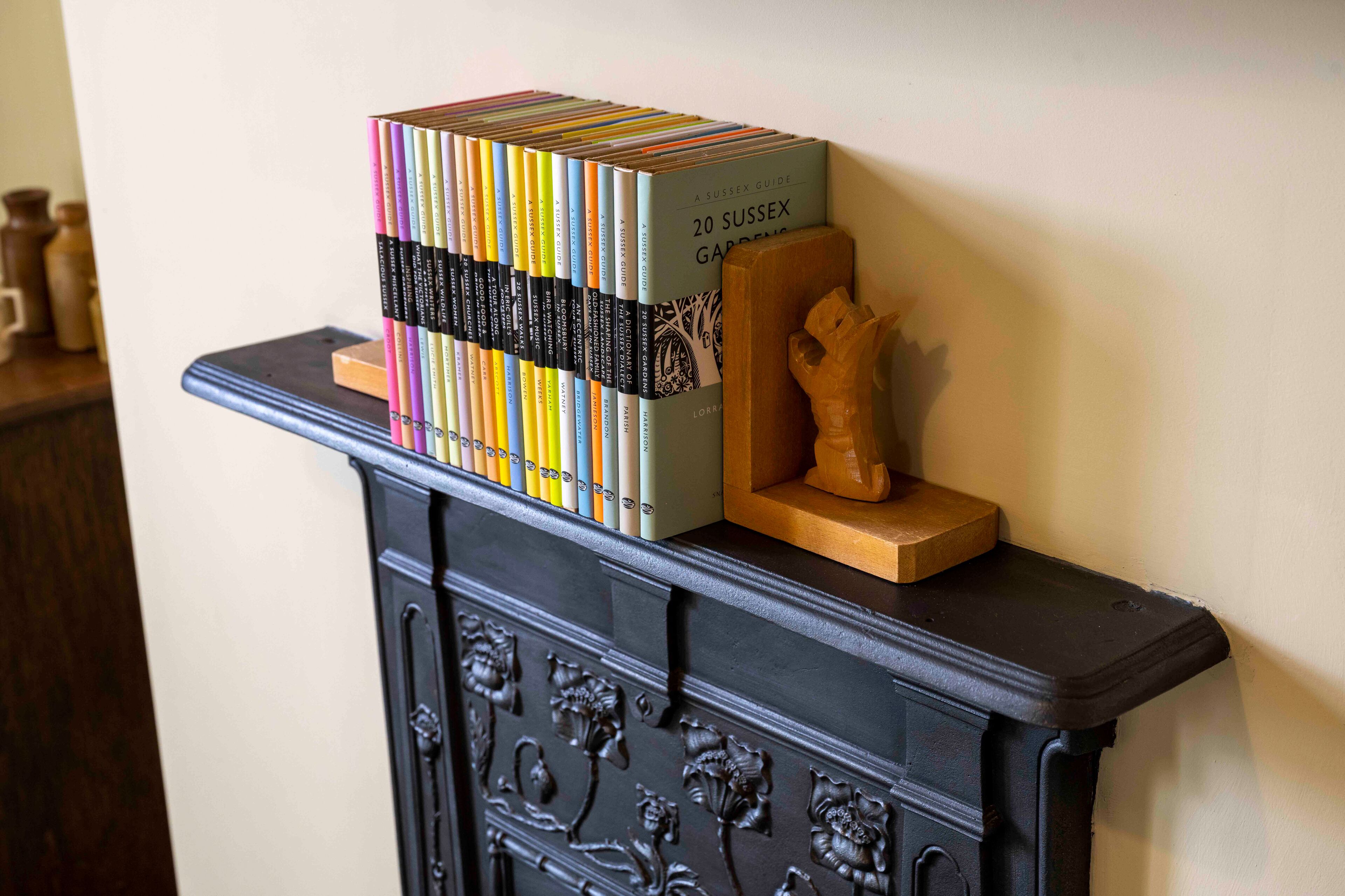 A stack of books titled "20 Sussex Gardens" on a black cabinet with floral carvings.