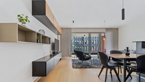 A modern dining area with a wooden floor, black chairs, and a table. There is a black pendant light above the table. - Stylish Apt in Cloche dOr w balconyID233 (Luxembourg City)