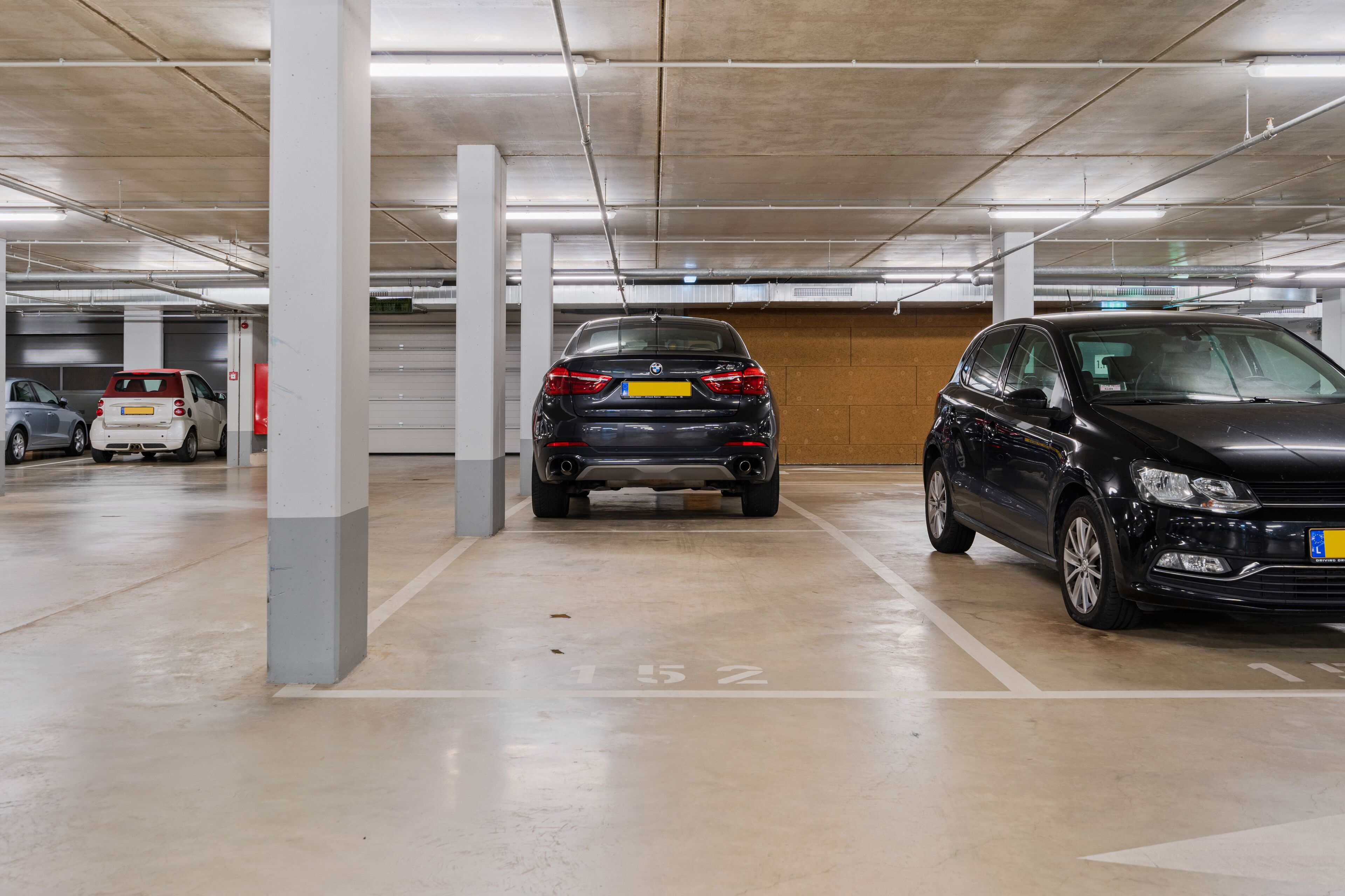 Um parque de estacionamento com vários níveis e carros estacionados em espaços demarcados.