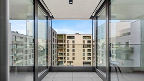 A modern apartment with large glass windows, a tiled floor, and a view of neighboring buildings. - Stylish Apt in Cloche dOr w balconyID233 (Luxembourg City)