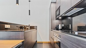 A modern kitchen with dark wood cabinets, a wooden countertop, and stainless steel appliances. - Stylish Apt in Cloche dOr w balconyID233 (Luxembourg City)