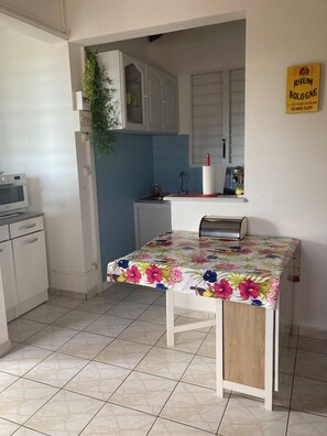 Une cuisine compacte comprenant une petite table à manger, un four à micro-ondes, des placards et un panneau indiquant la présence d’un bar à rhum.