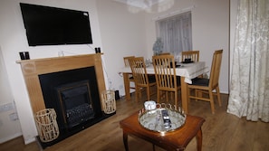 Cozy living room with a fireplace, dining area, and television, perfect for relaxing and enjoying meals together.
