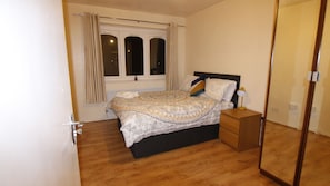 Cozy retreat with a large bed, bedside table, and lamp.