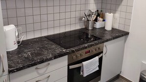 Moderni keittiö, jossa on valkoiset kaapit, musta marmoritaso, sisäänrakennettu uuni ja ruostumattomasta teräksestä valmistettu pesuallas.