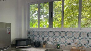 Une cuisine équipée d’un four à micro-ondes, d’un évier et d’une fenêtre donnant sur les arbres.