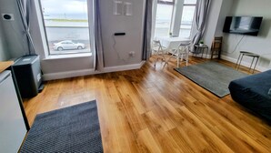 Ein modernes Zimmer mit Holzboden, einem Bett, einem Schreibtisch und einem Fernseher.
