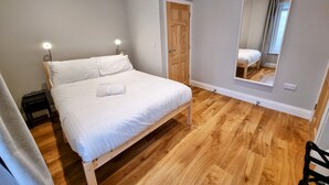Ein Schlafzimmer mit einem hölzernen Bett, einem Nachttisch, einem Spiegel und einer Tür.