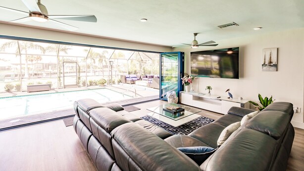 A modern living room with a large leather sofa, a coffee table, and a TV mounted on the wall. -  BRING YOUR SAIL BOAT  (Punta Gorda)