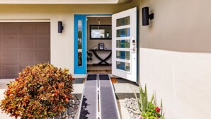 A modern house entrance with a garage, a blue door, and a pathway leading to a room with a TV and a small table. -  BRING YOUR SAIL BOAT  (Punta Gorda)