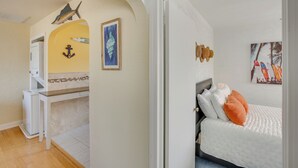 Een hotelkamer met een bed, een klein bureau, een koelkast en een deur naar een andere kamer.