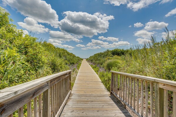 A wooden boardwalk leading through a natural landscape with dense vegetation on both sides.