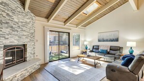 A spacious living room with a stone fireplace, wooden ceiling beams, a sofa, and a recliner. - Stylish Incline Village Vacation Rental w/ A/c! (Incline Village)