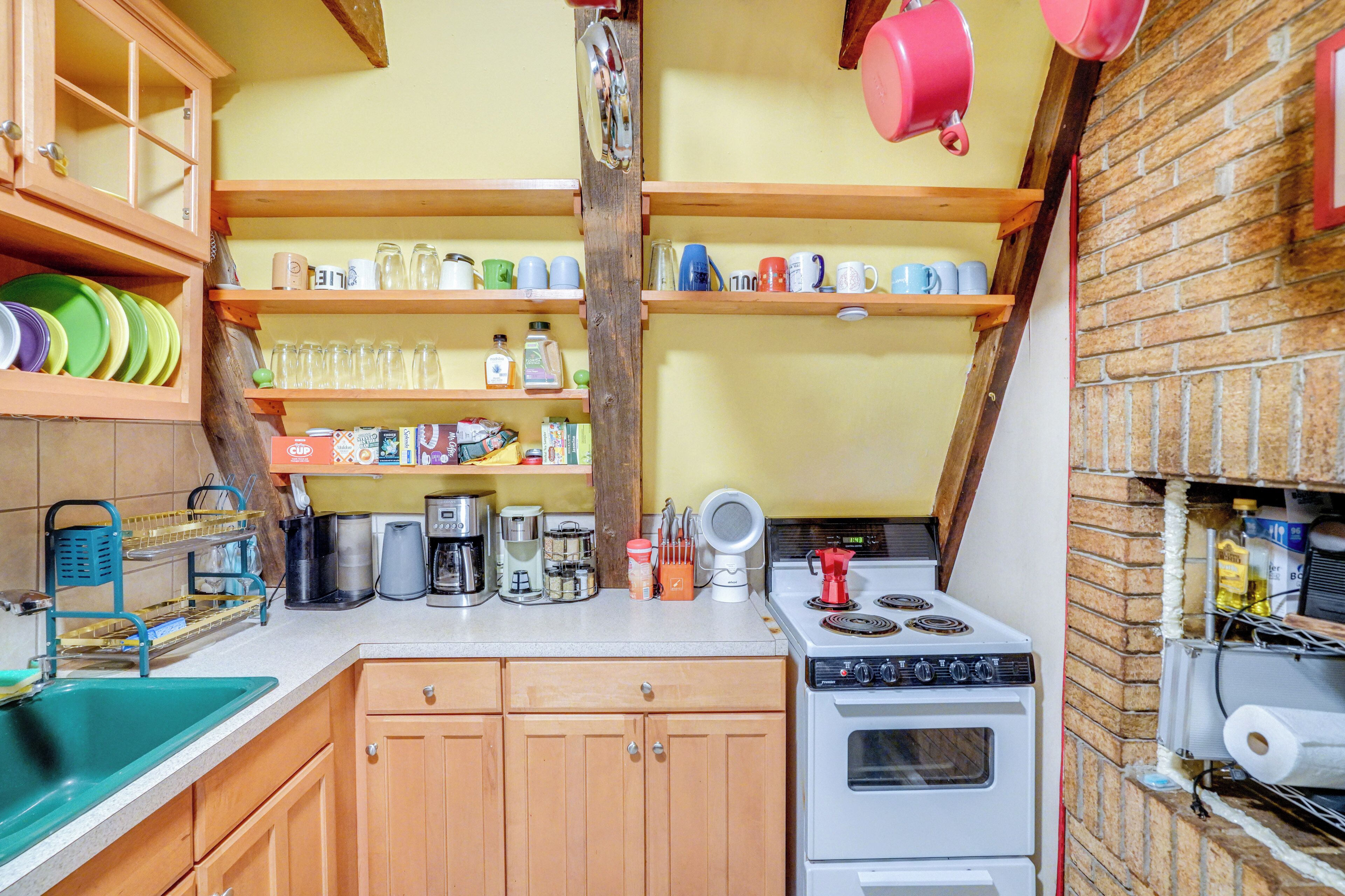 A compact kitchen with wooden cabinets, a stove, and various kitchen appliances.