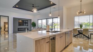 Une cuisine moderne dotée d’un grand îlot central, de meubles en bois et d’un coin repas avec une table et des chaises.
