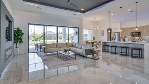 Un salon spacieux, doté d’un grand canapé, d’une table basse et offrant une vue sur l’extérieur grâce à de grandes fenêtres.